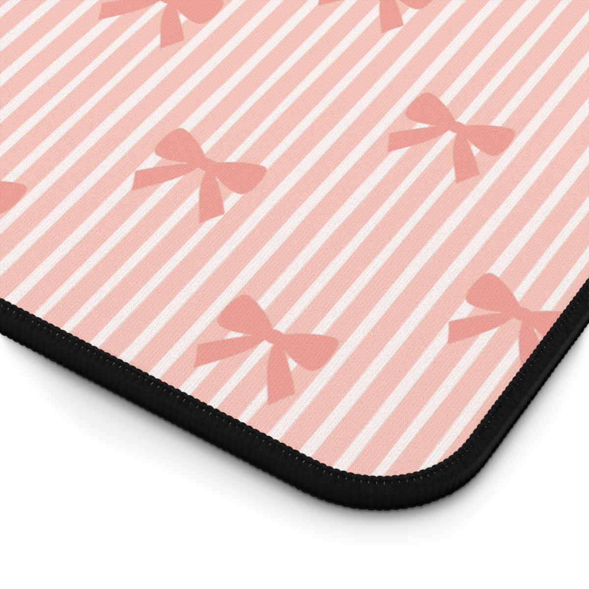 A close-up of a rectangular mouse pad with a pink and white striped pattern decorated with pink bows, finished with a black stitched border.