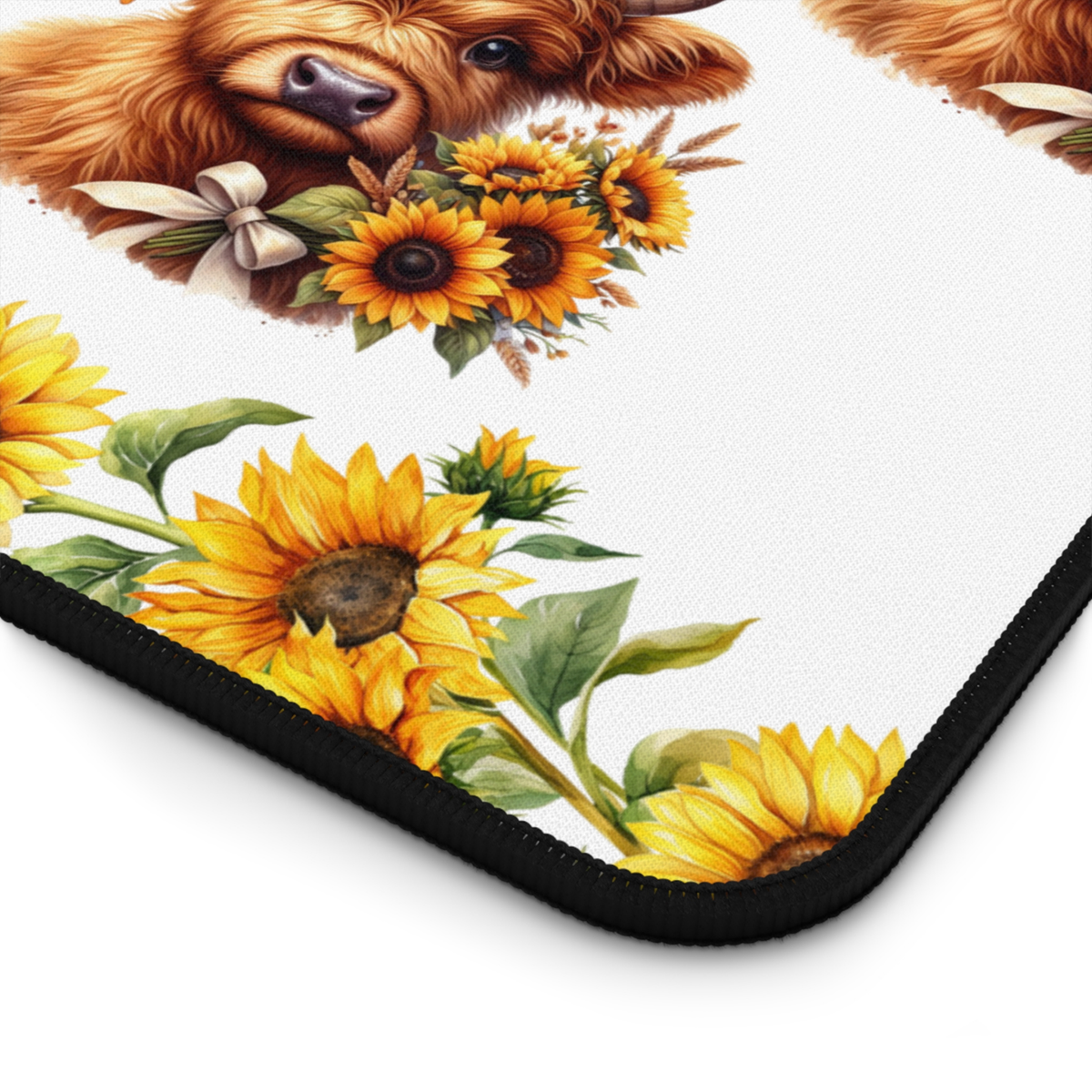 A close-up of a printed mousepad or desk mat showing a highland cow with sunflowers and green leaves on a white background, with a black border visible around the edge.