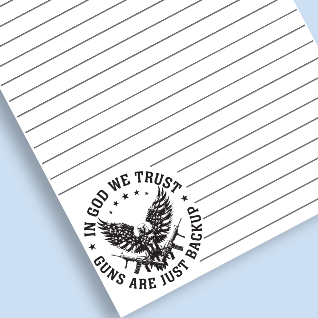 A close-up of a lined white paper sheet with a black printed emblem and the text 'IN GOD WE TRUST GUNS ARE JUST BACKUP,' shown on a light blue background.